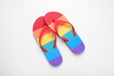 Stylish rainbow flip flops on white background, top view