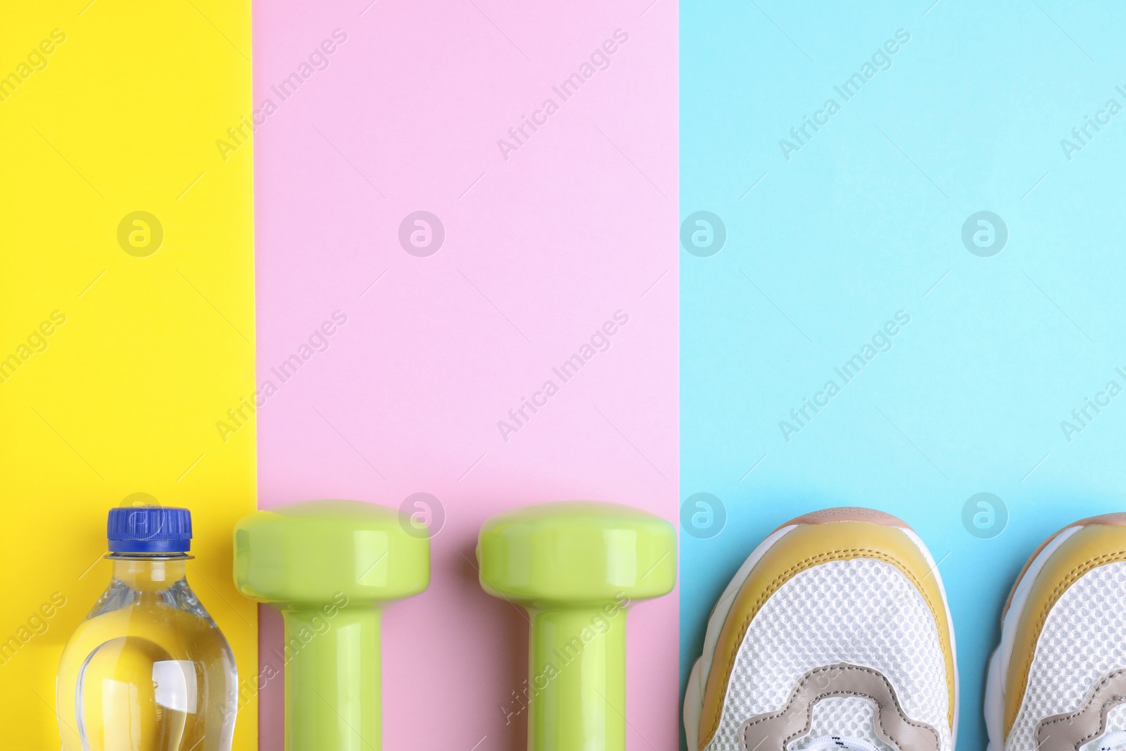 Photo of Vinyl dumbbells, sneakers and bottle of water on color background, flat lay. Space for text