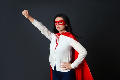 Photo of Confident businesswoman wearing superhero cape and mask on grey background