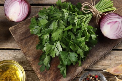 Photo of Board with fresh parsley and other products on wooden table