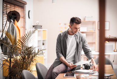 Journalist with papers at workplace in office