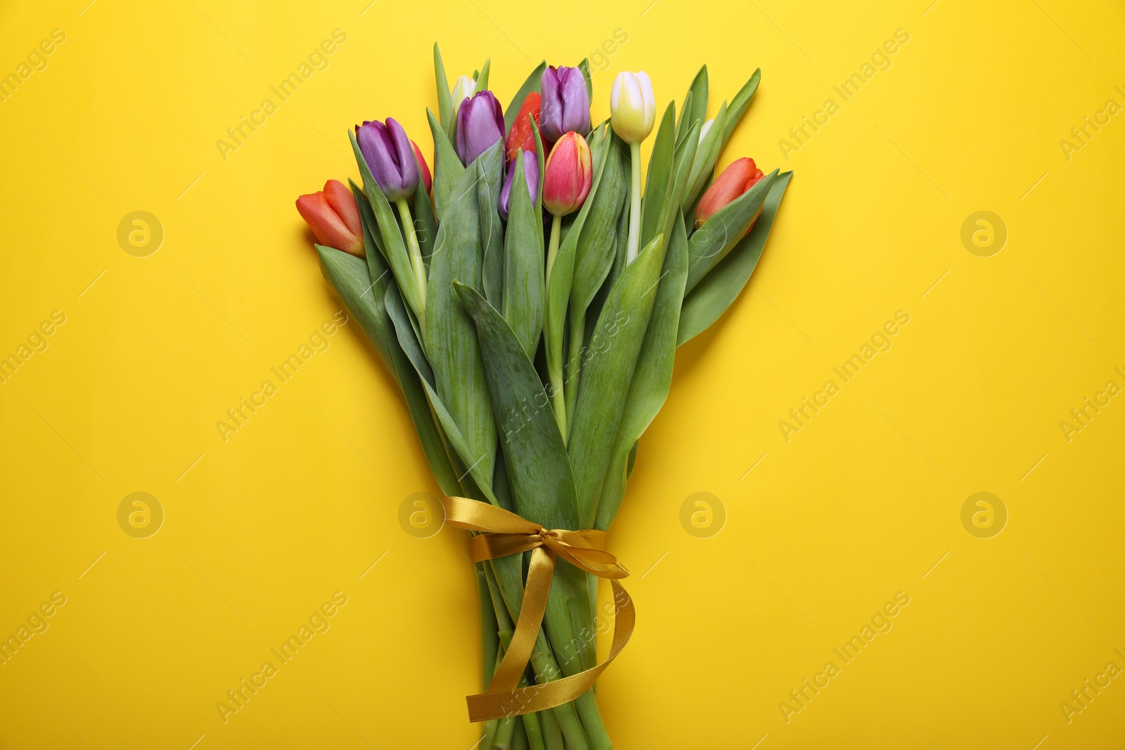 Photo of Bunch of beautiful tulips on yellow background, top view