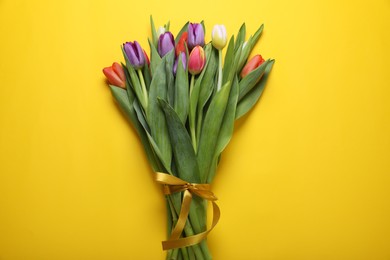 Bunch of beautiful tulips on yellow background, top view