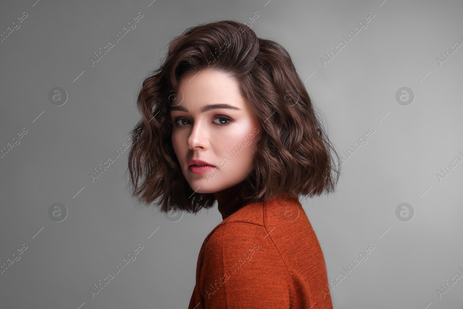 Photo of Portrait of beautiful young woman with wavy hairstyle on grey background