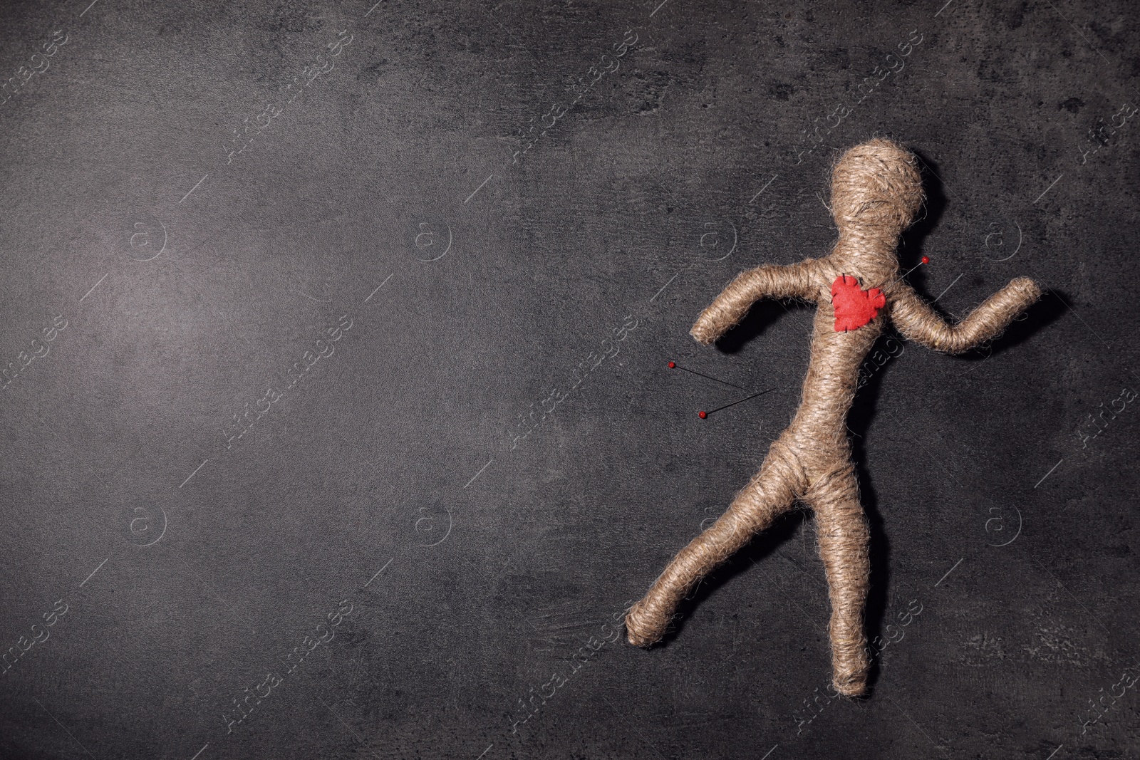 Photo of Voodoo doll with pin in heart on grey table, top view. Space for text