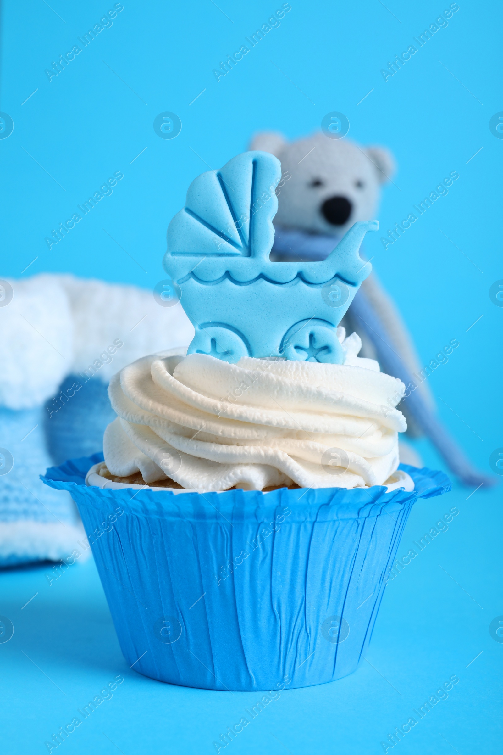 Photo of Beautifully decorated baby shower cupcake with cream and boy topper on light blue background