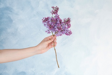 Young woman holding beautiful blossoming lilac on color background. Spring flowers