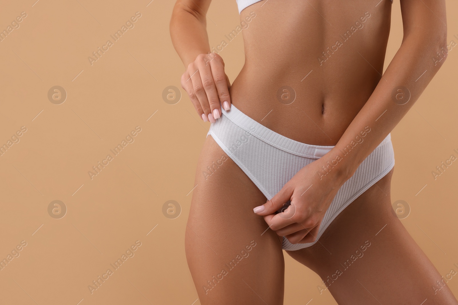 Photo of Young woman in stylish white bikini on beige background, closeup. Space for text