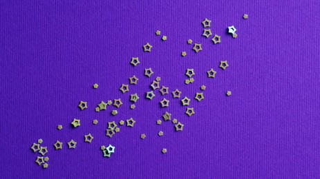 Photo of Many silver star shaped sequins on purple background, flat lay