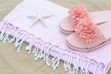 Photo of Blanket with stylish slippers and starfish on sand outdoors, closeup. Beach accessories