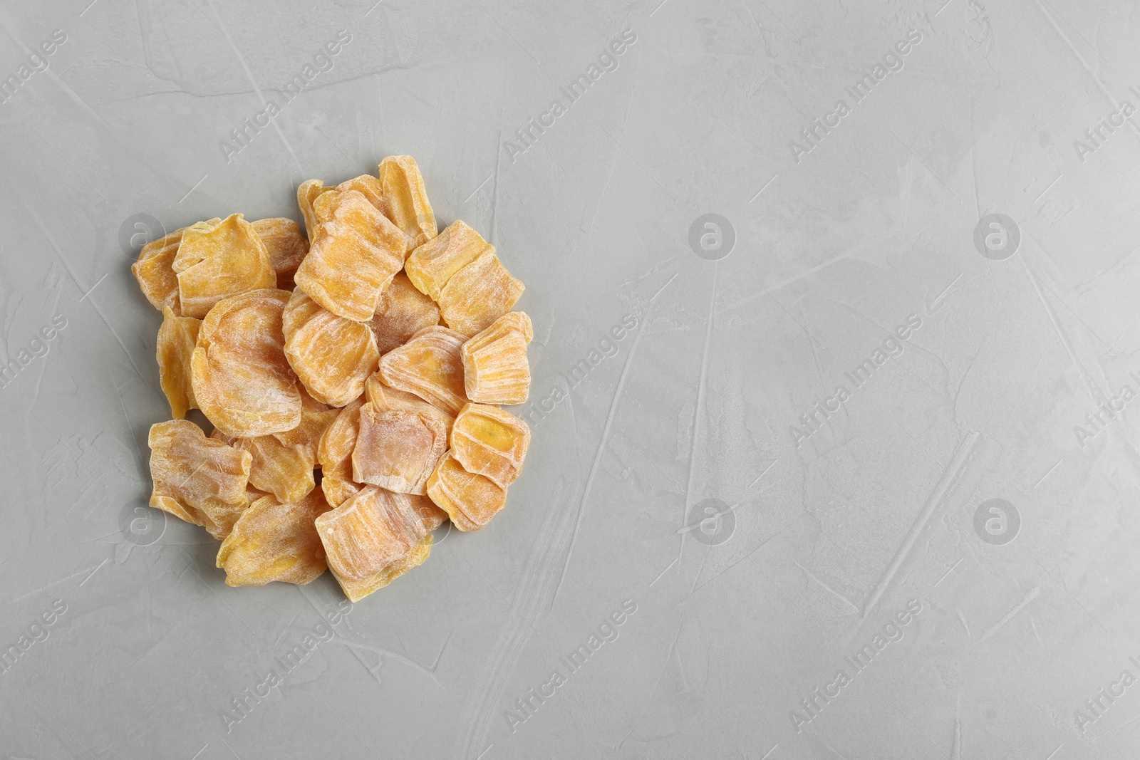 Photo of Delicious dried jackfruit slices on grey table, top view. Space for text