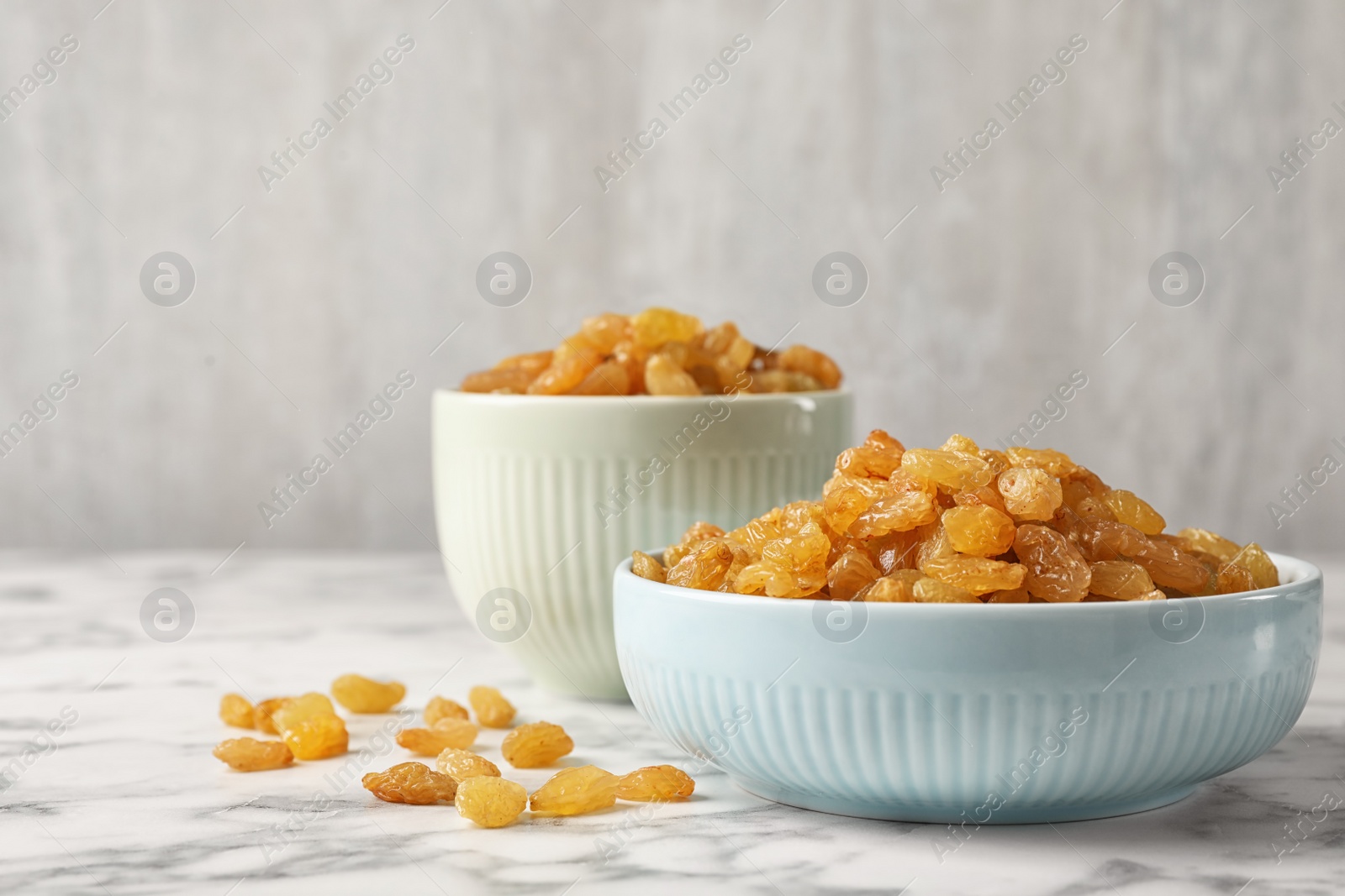 Photo of Bowls with raisins on marble table. Dried fruit as healthy snack