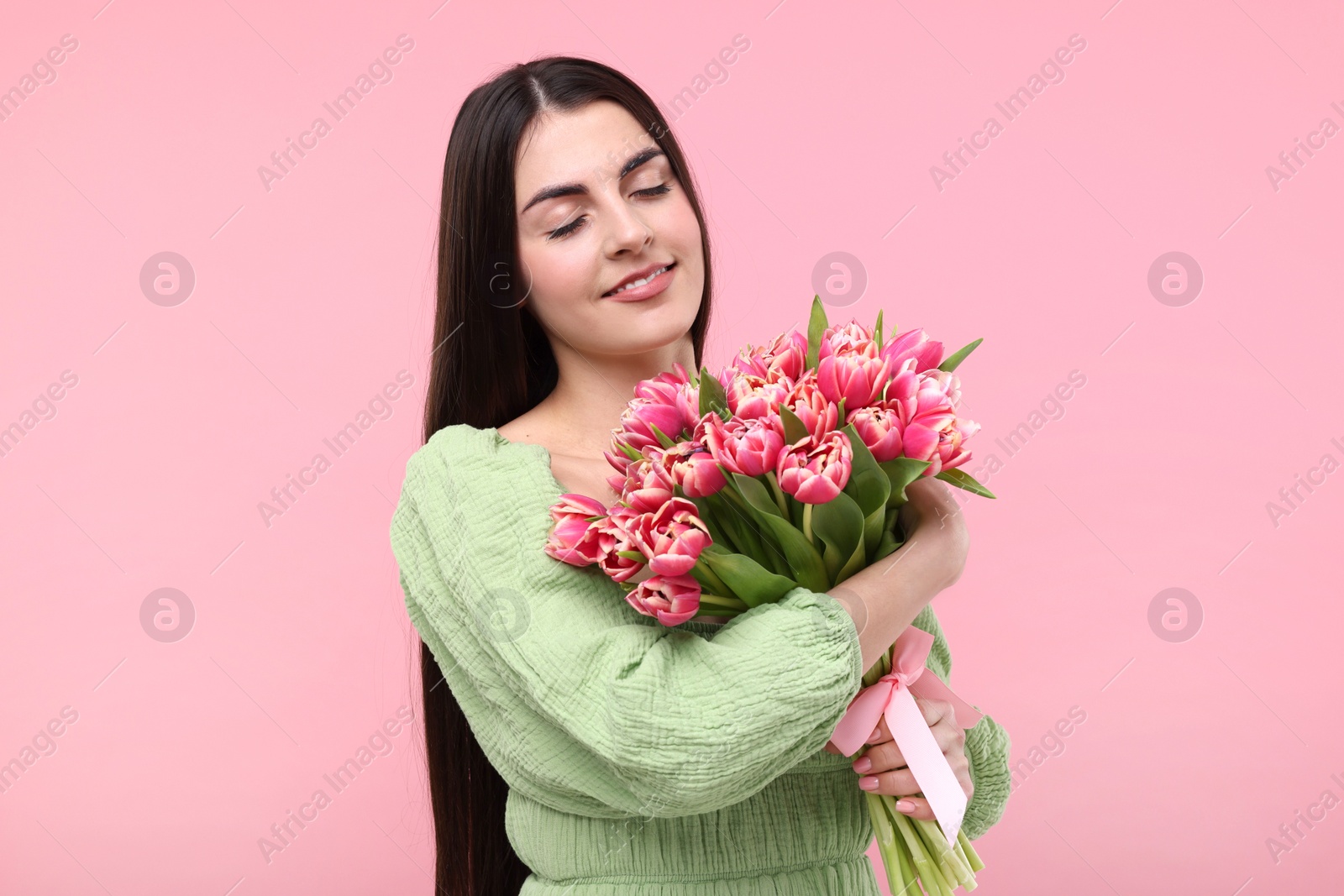 Photo of Happy young woman with beautiful bouquet on dusty pink background