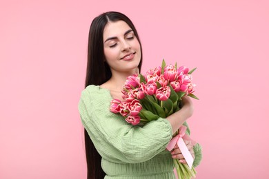 Happy young woman with beautiful bouquet on dusty pink background