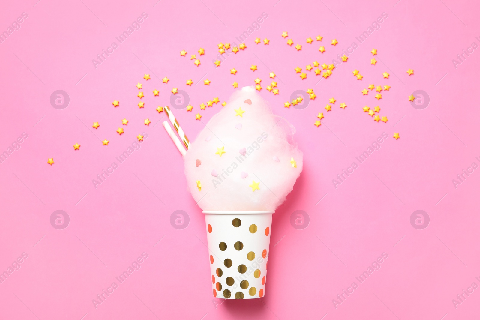 Photo of Cup with yummy cotton candy and sprinkles on color background, top view