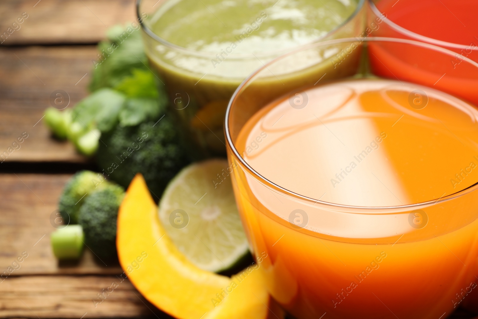 Photo of Delicious vegetable juices and fresh ingredients on wooden table, closeup