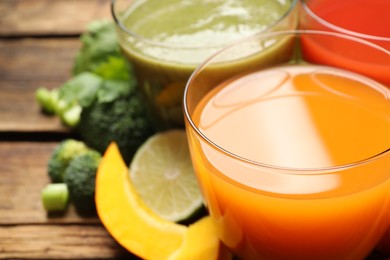 Delicious vegetable juices and fresh ingredients on wooden table, closeup