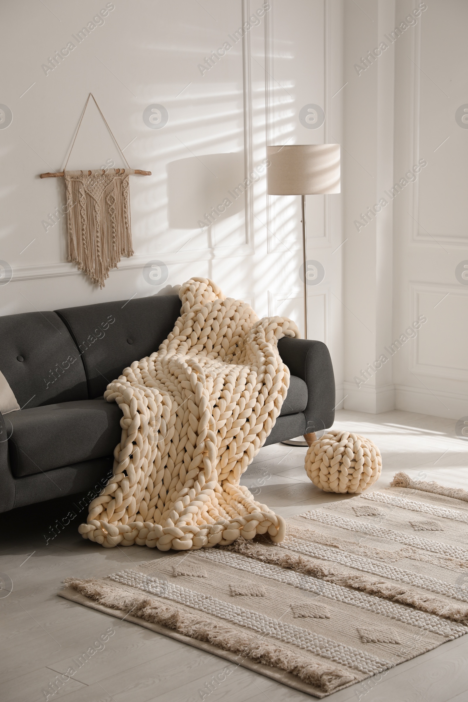 Photo of Soft chunky knit blanket on sofa in living room. Interior design