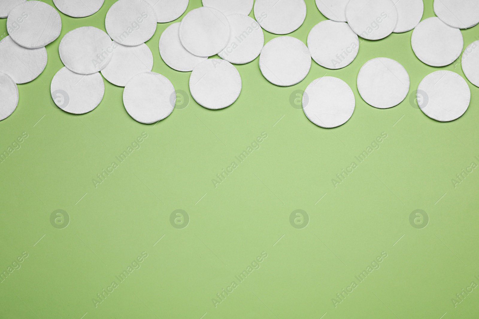 Photo of Many cotton pads on green background, flat lay. Space for text