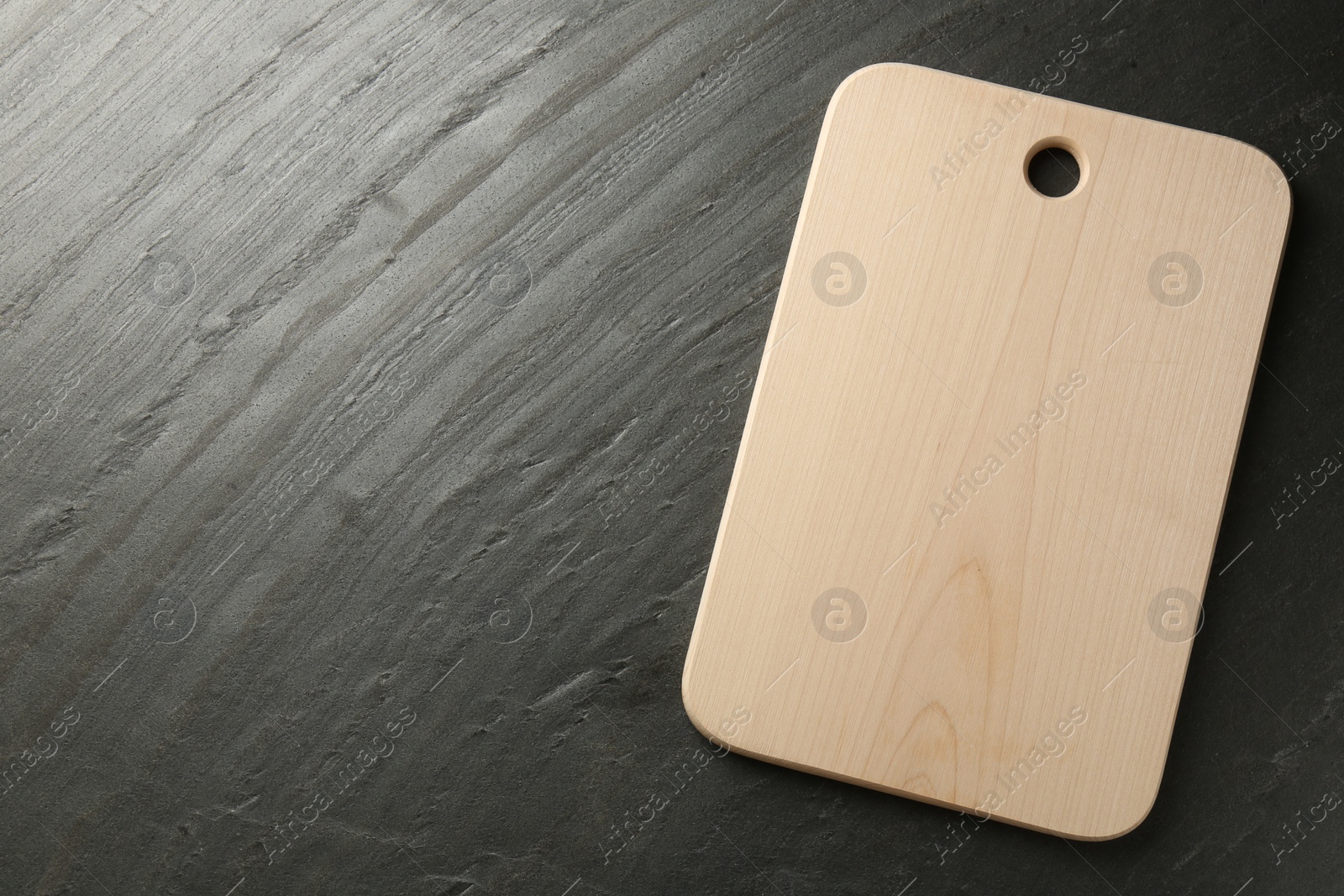 Photo of One wooden cutting board on dark grey table, top view. Space for text