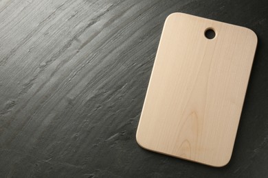Photo of One wooden cutting board on dark grey table, top view. Space for text