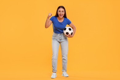 Happy fan holding soccer ball and celebrating on yellow background