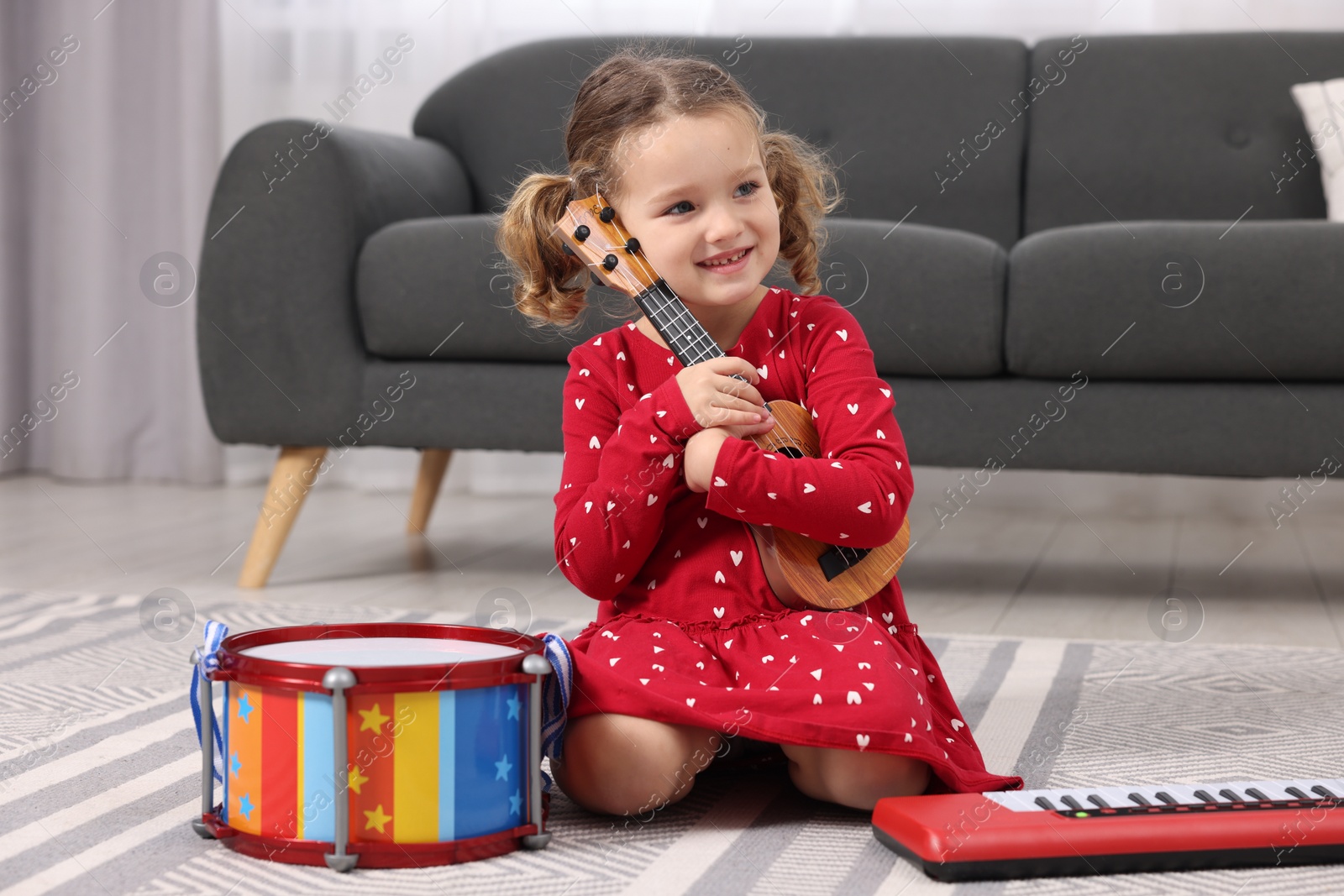 Photo of Little girl playing toy guitar at home