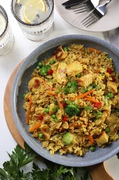 Photo of Tasty rice with meat and vegetables in frying pan served on white table, flat lay