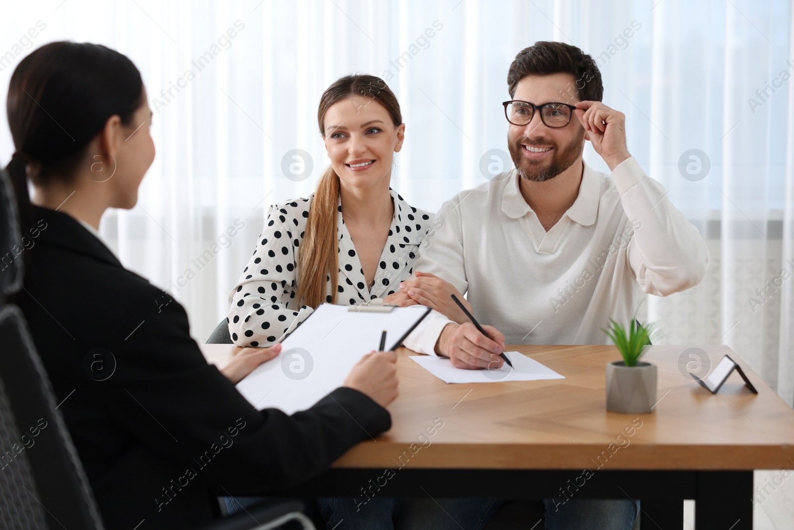 Photo of Happy couple signing document in lawyer's office