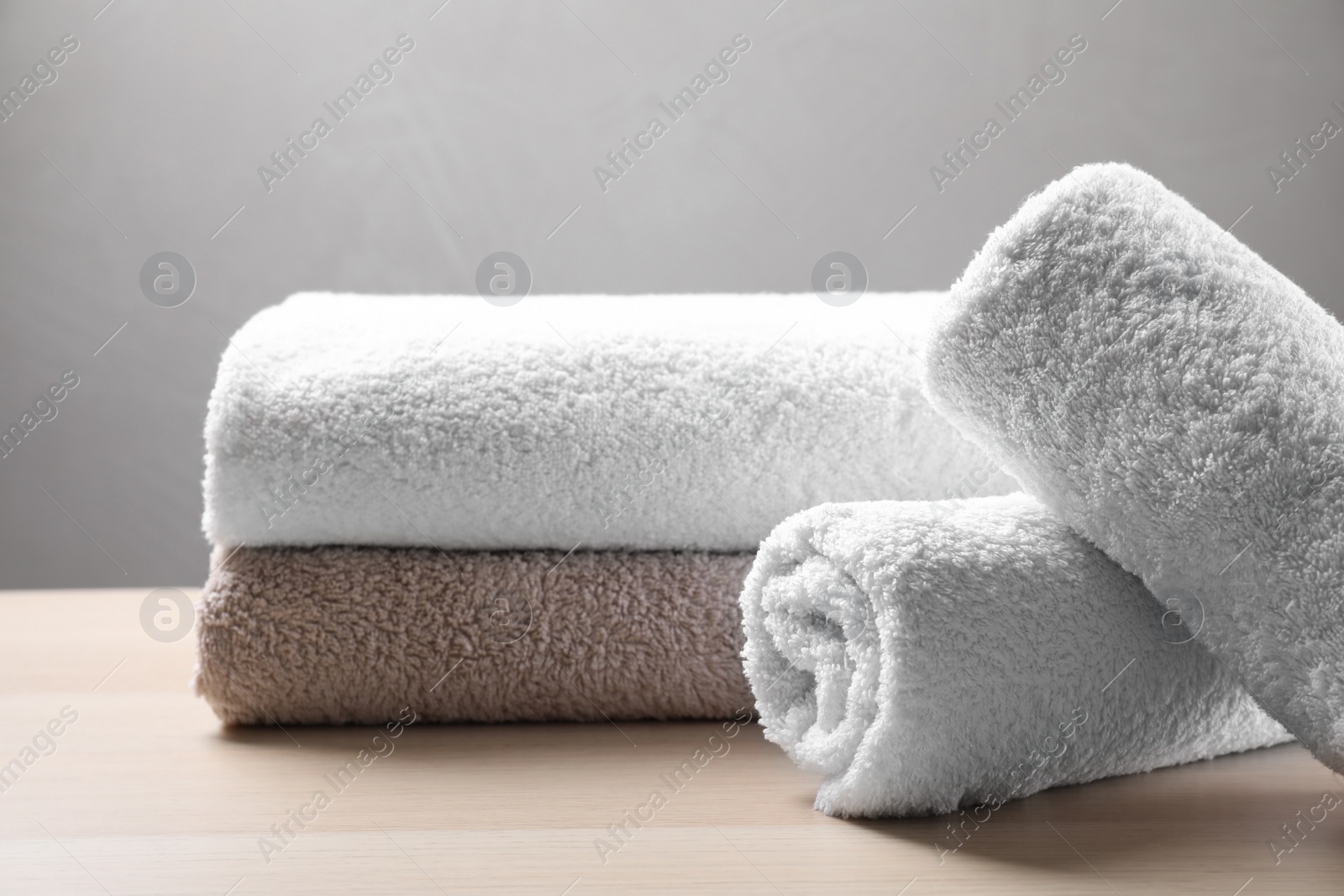 Photo of Rolled and folded soft towels on wooden table