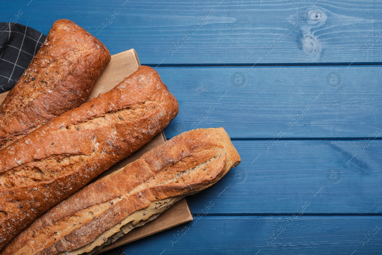 Photo of Tasty buckwheat baguettes on blue wooden table, flat lay. Space for text