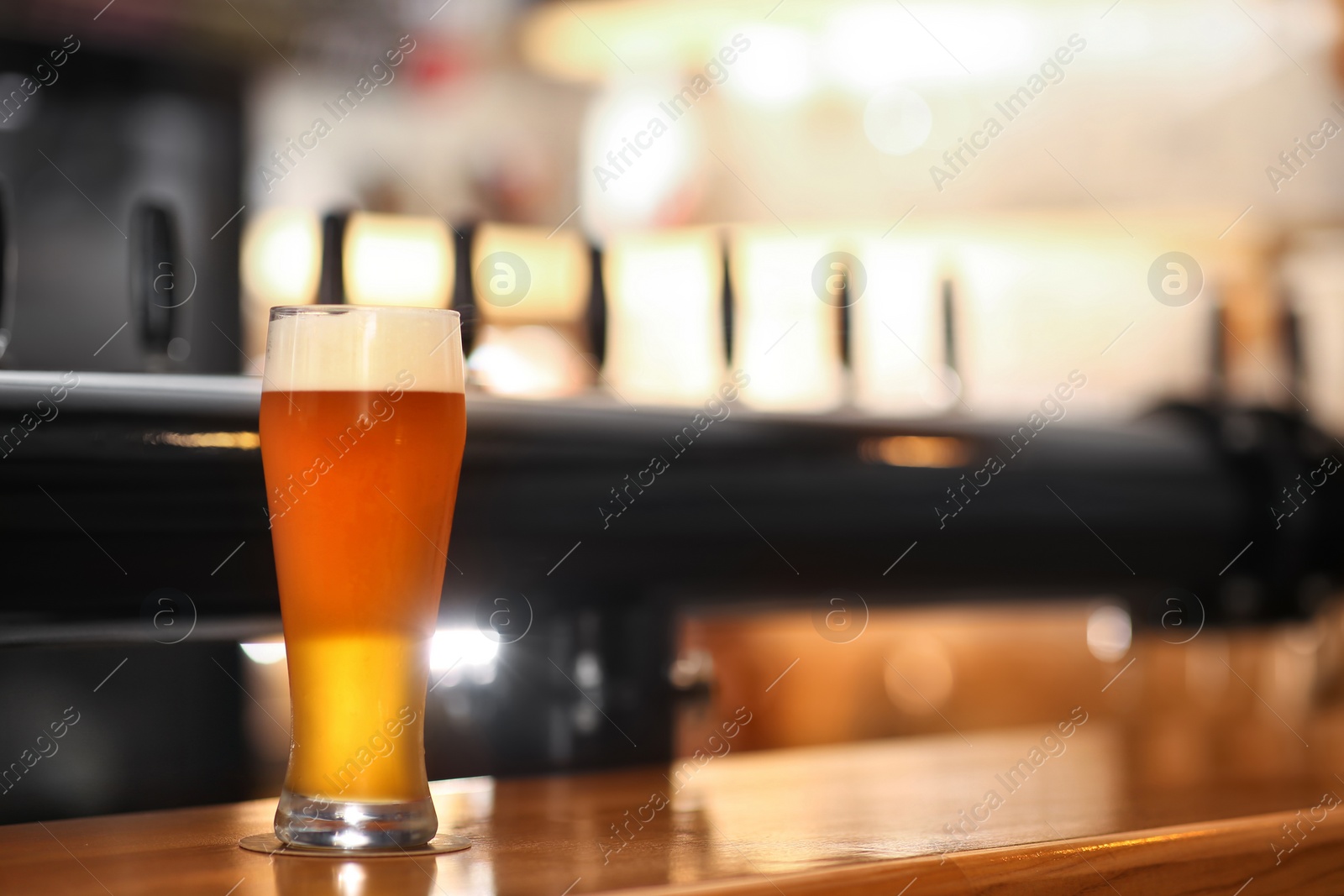 Photo of Glass of cold tasty beer on bar counter, space for text