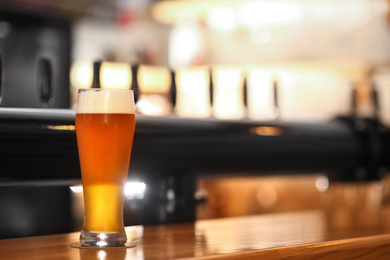 Photo of Glass of cold tasty beer on bar counter, space for text