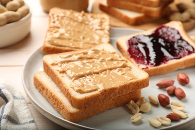 Photo of Delicious toasts with peanut butter, jam and nuts on table, closeup