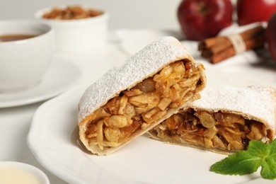 Photo of Delicious strudel with apples, nuts and raisins on plate, closeup