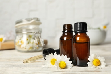 Photo of Composition with bottles of chamomile essential oil on table. Space for text