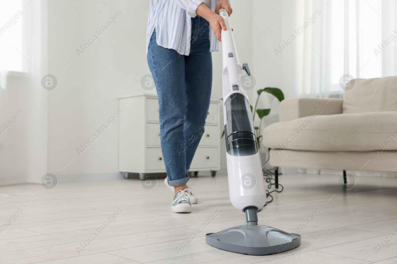 Photo of Woman cleaning floor with steam mop at home, closeup