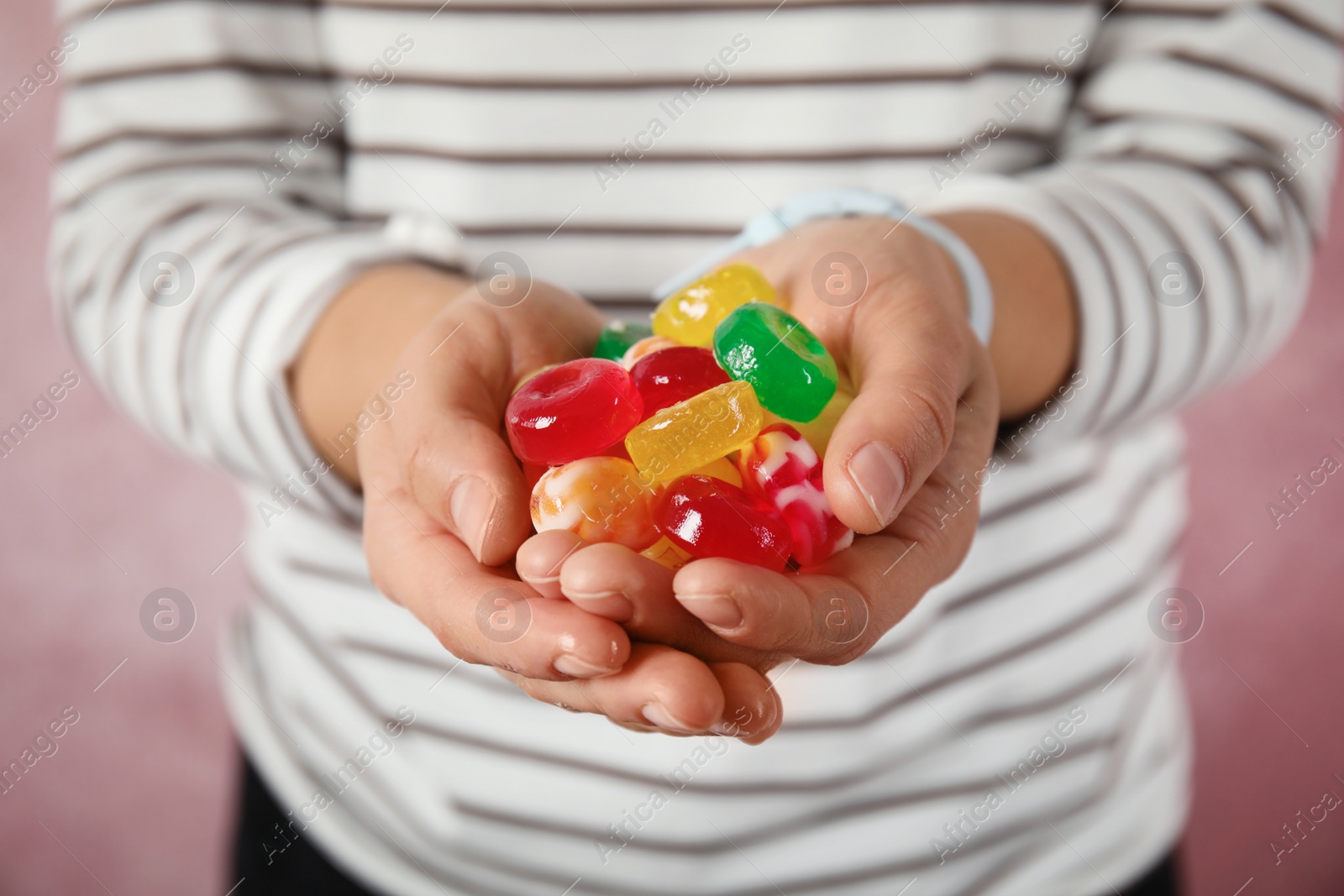 Photo of Woman holding many colorful candies on color background, closeup