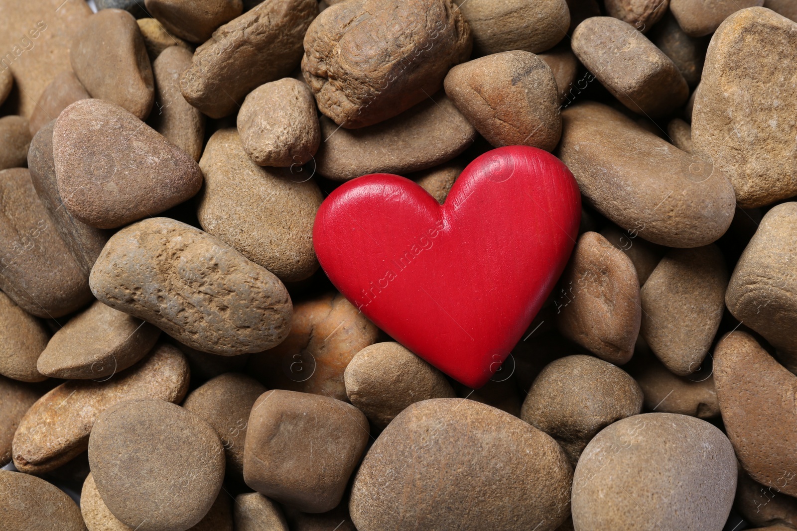 Photo of Red decorative heart on stones, top view