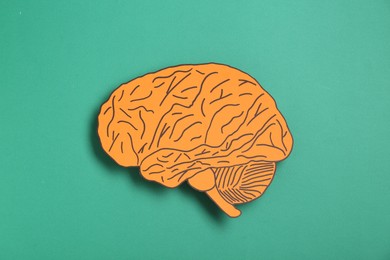 Photo of Paper cutout of human brain on turquoise background, top view