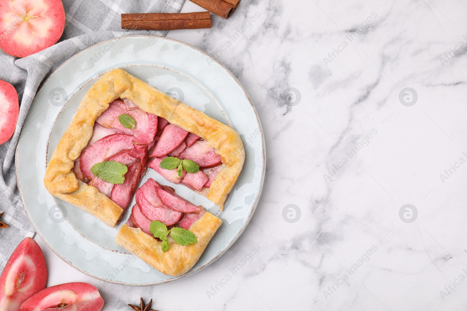 Photo of Delicious apple galette with mint and ingredients on white marble table, flat lay. Space for text