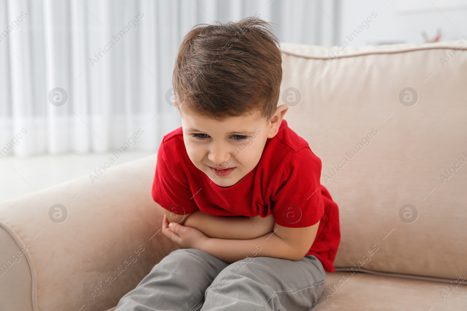 Photo of Little boy suffering from nausea in living room