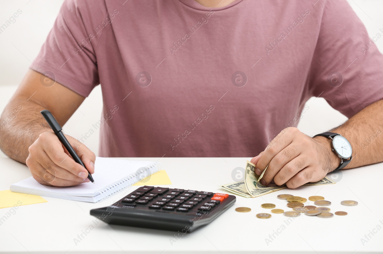 Photo of Young man counting money at white table indoors, closeup