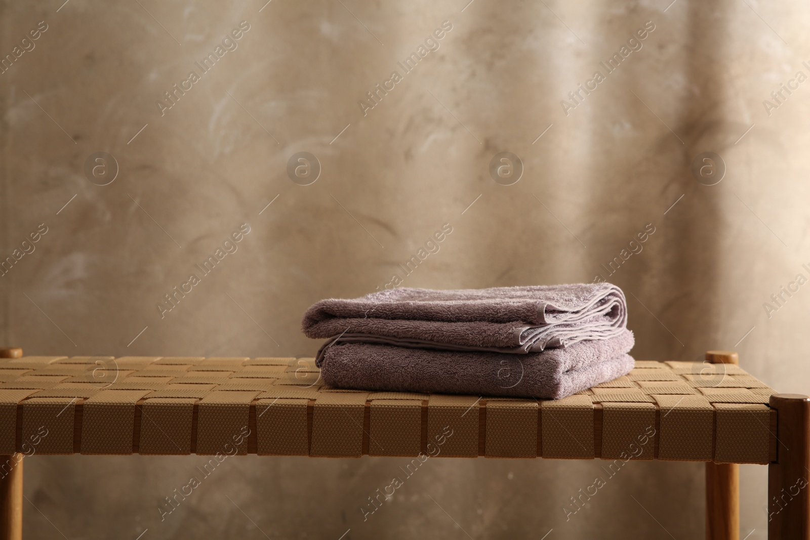 Photo of Soft terry towels on wicker bench indoors