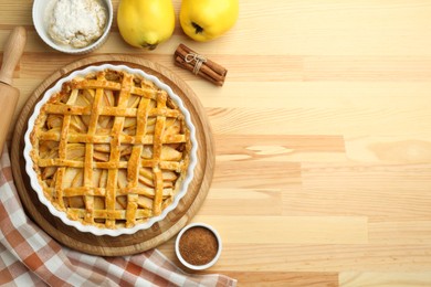 Photo of Tasty homemade quince pie and ingredients on wooden table, flat lay. Space for text