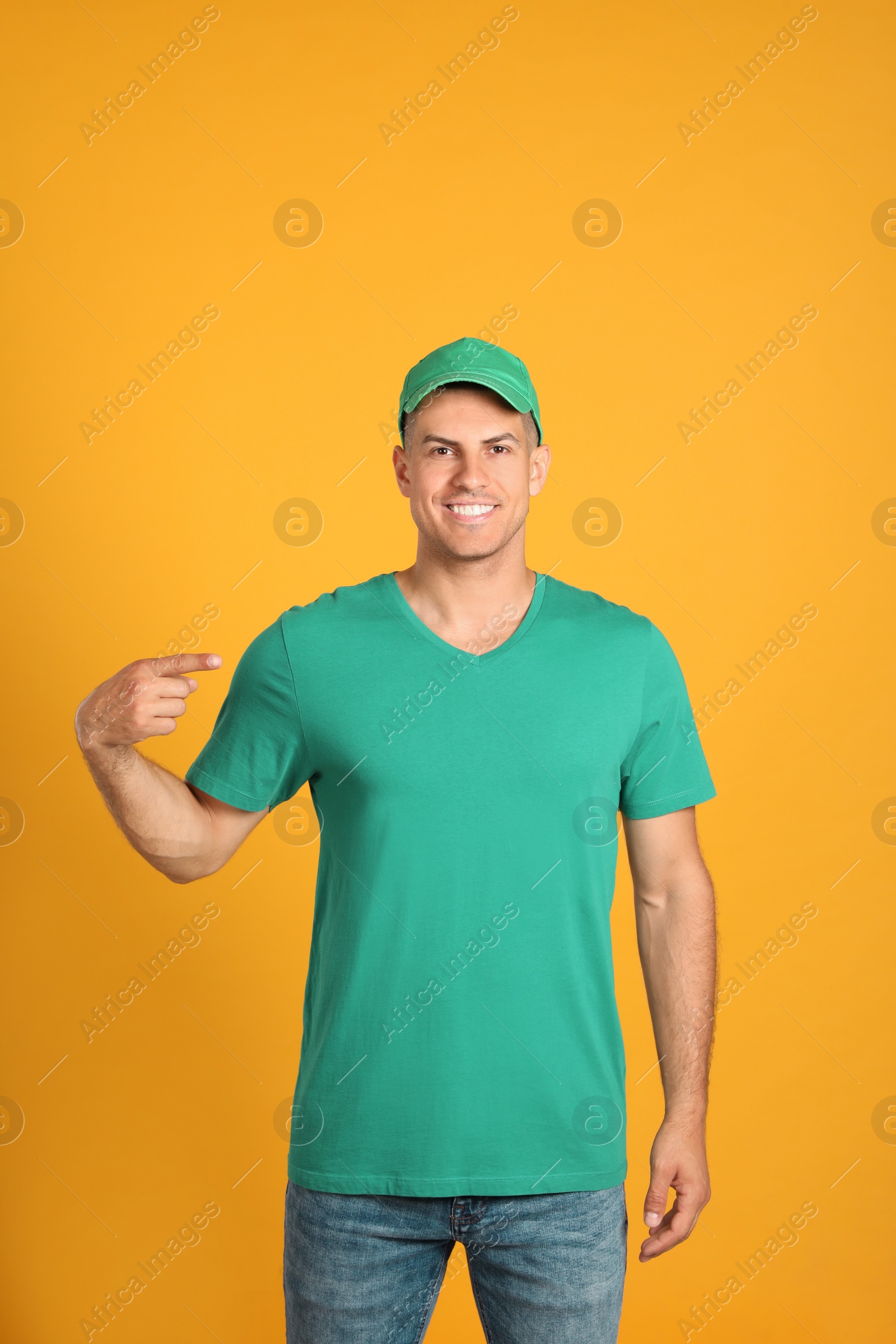 Photo of Happy man in green cap and tshirt on yellow background. Mockup for design