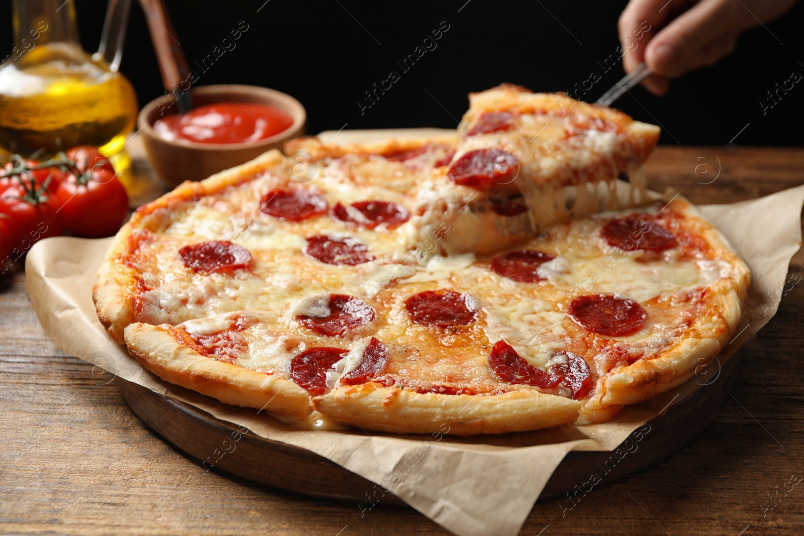 Photo of Woman taking slice of tasty pepperoni pizza at wooden table, closeup