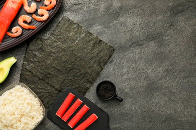 Flat lay composition with ingredients for sushi on dark textured table. Space for text