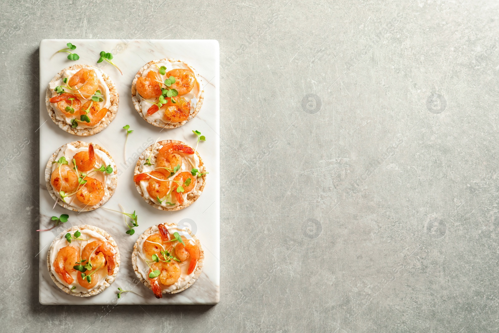 Photo of Delicious small sandwiches with shrimps on marble board