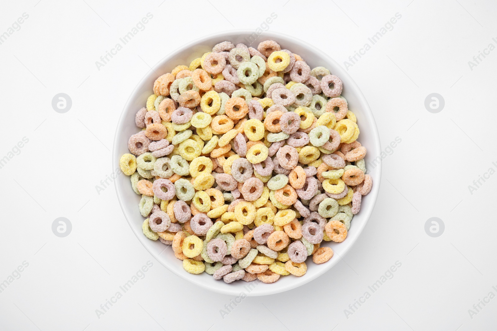 Photo of Tasty cereal rings in bowl on white table, top view